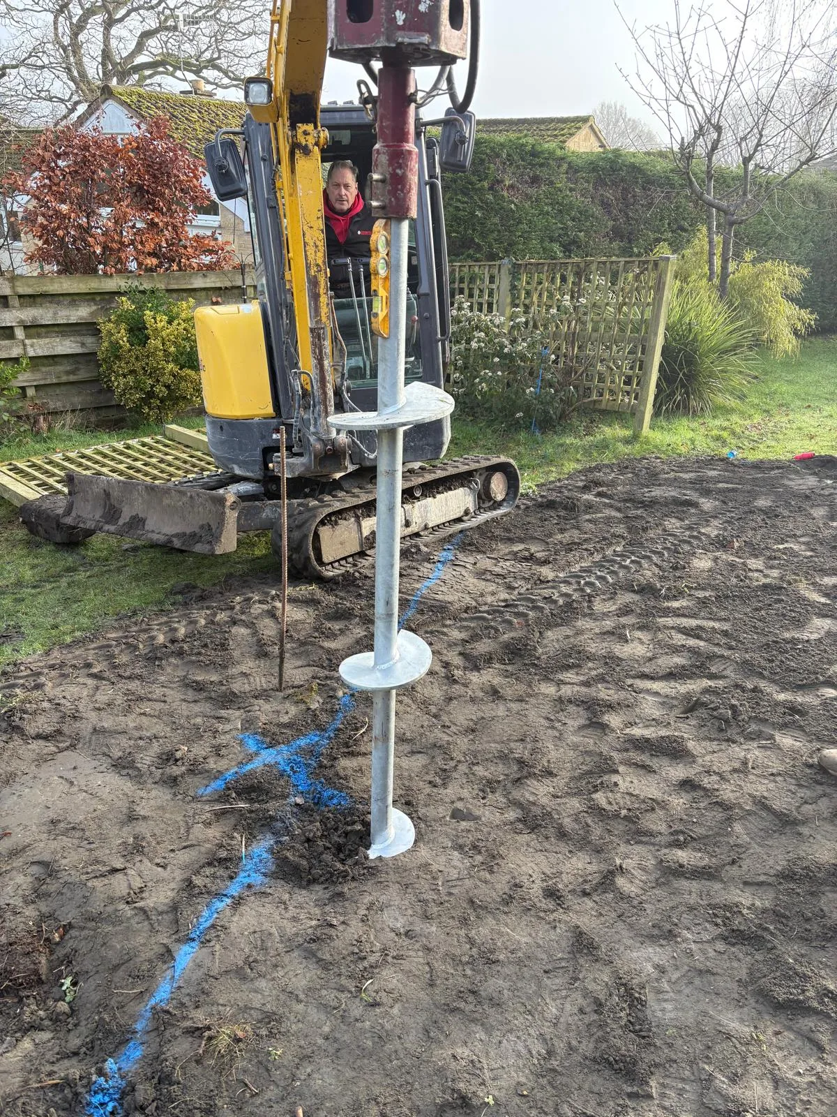 Galvanised screw pile foundation being installed by excavator